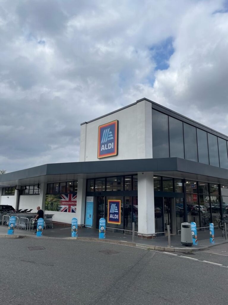 曇り空の下、ガラス張りの外観が特徴的なALDIの店舗入口。